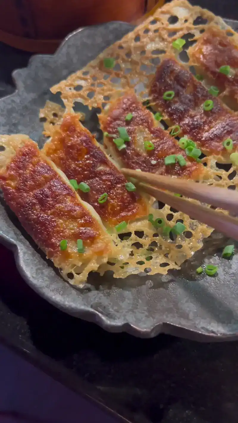 Pan-fried gyoza joined by a crisp lace of batter, topped with spring onion / เกี๊ยวซ่าทอดติดแผ่นแป้งกรอบ โรยต้นหอม