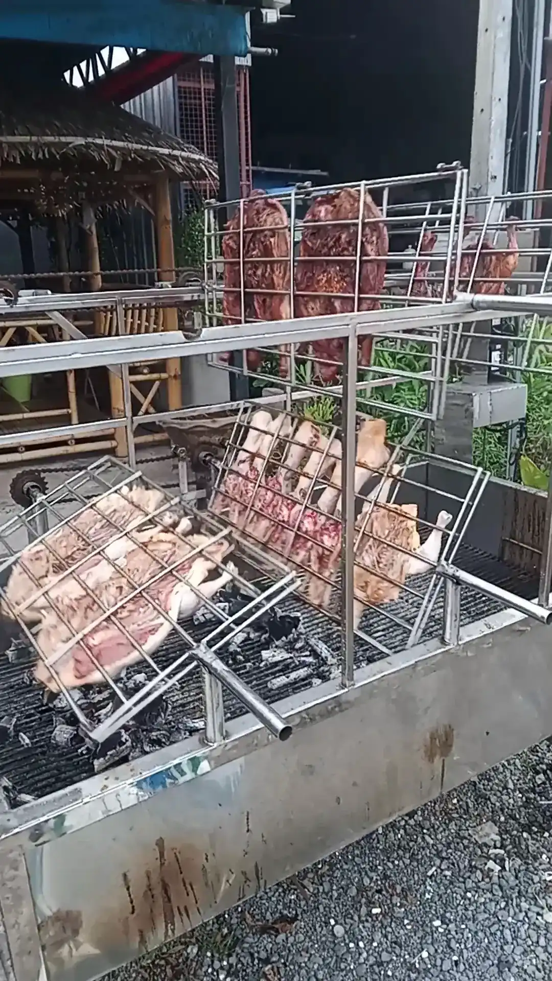 Out front: steel cages of chicken and marinated meat turning over charcoal, with a thatched sala behind