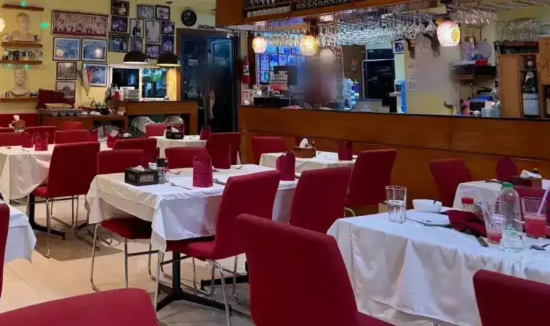 The dining room: white tablecloths, red chairs and the wooden bar