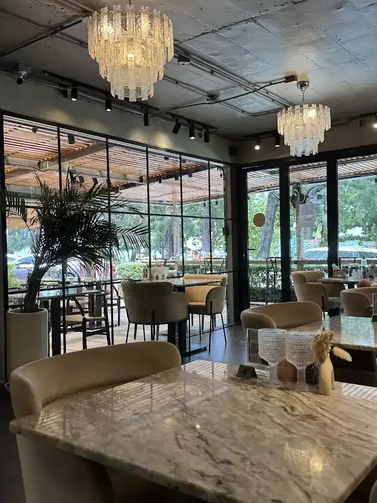 The dining room at L'ORANGE: marble tables, chandeliers and a steel-framed glass wall onto the terrace