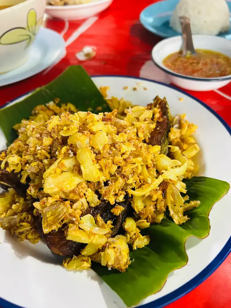 Fried fish under a heap of crisp golden topping, on a banana leaf