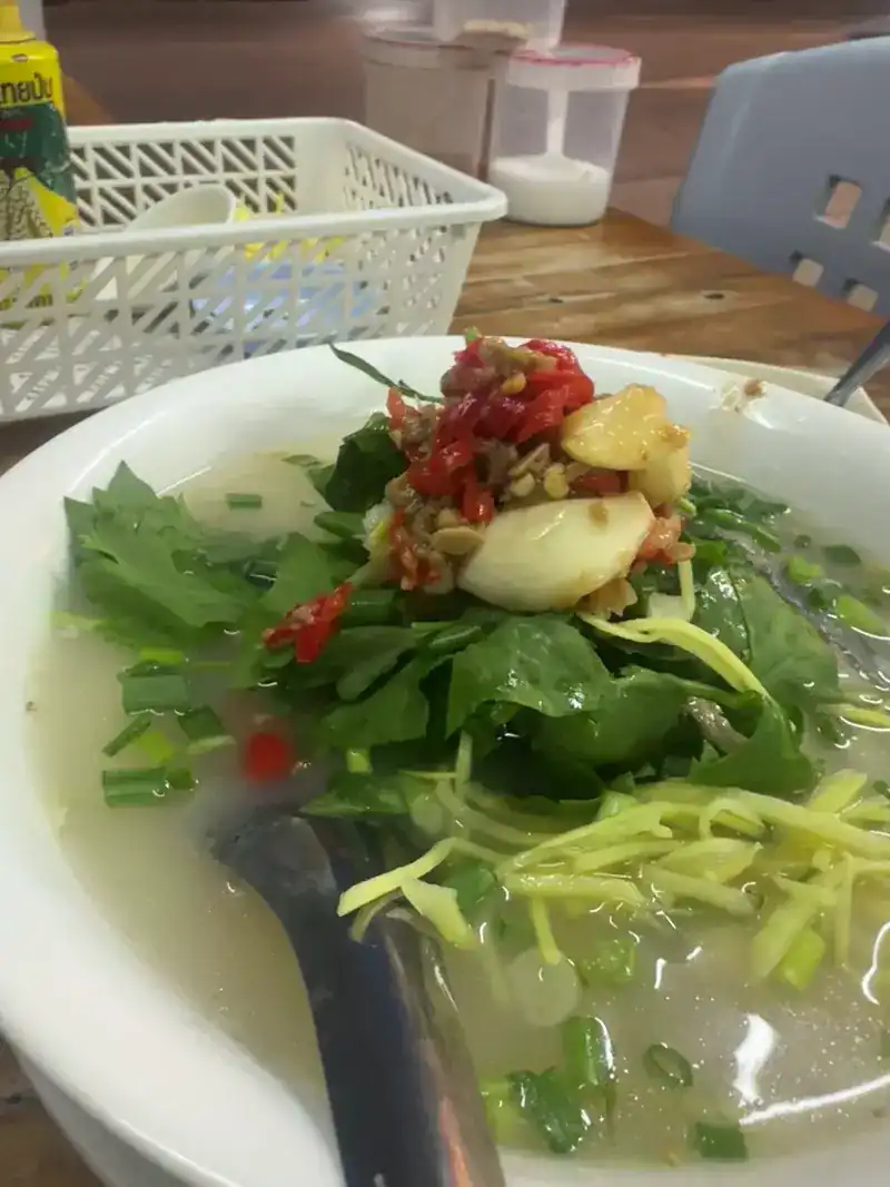 Fish rice porridge topped with chilli, greens and ginger