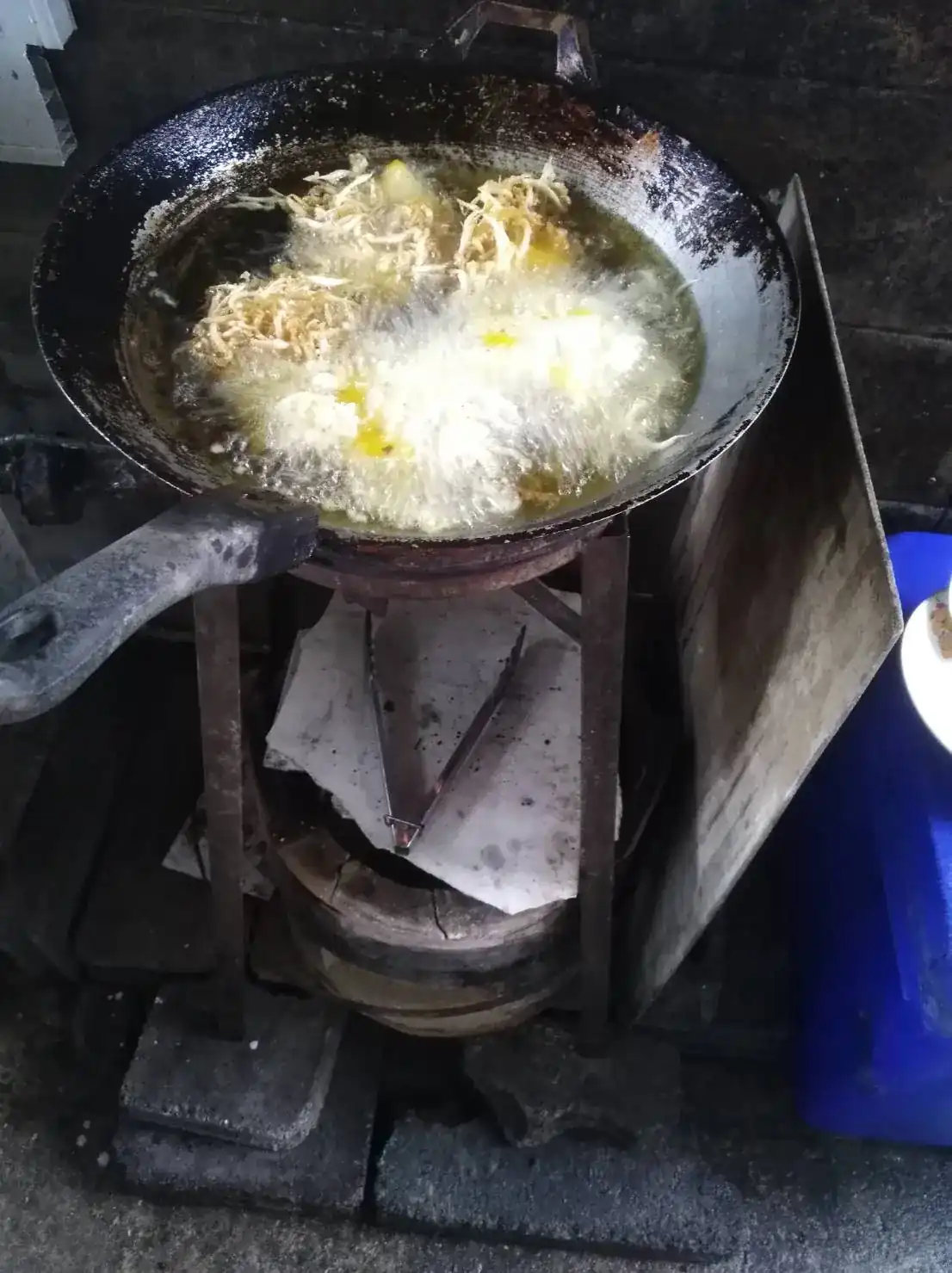 Eggs frying in bubbling oil in a well-used wok in the shop’s kitchen