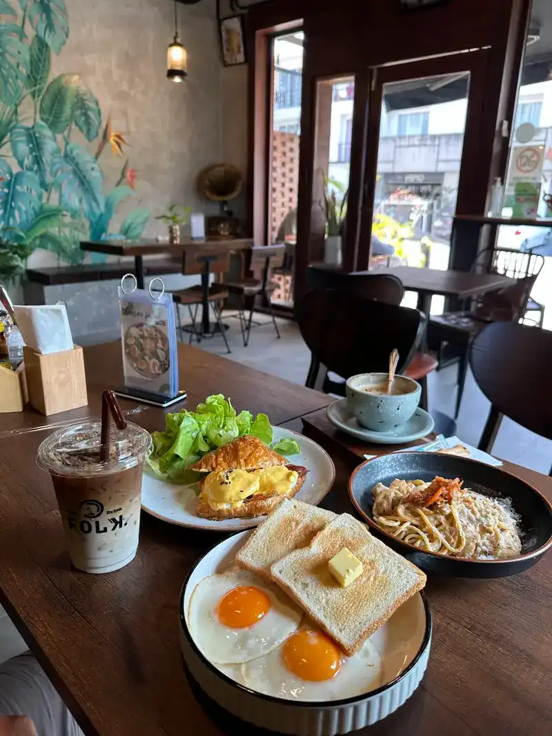 Fried eggs with toast, a croissant with eggs, creamy pasta and an iced drink in a Folk cup