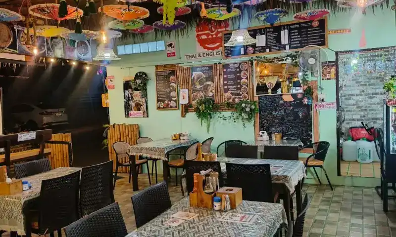 The mint-green dining room with patterned tablecloths, menu boards, a chalkboard and parasols along the ceiling