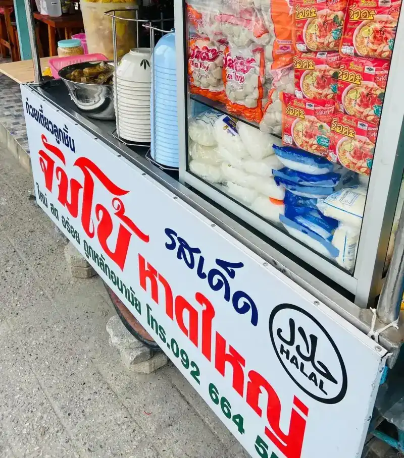 The noodle cart's sign: red lettering, the halal mark and the phone number