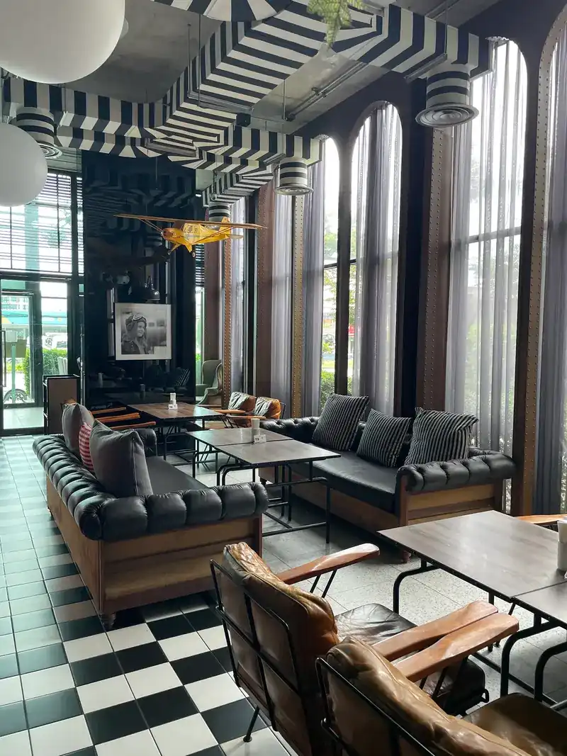 Tall windows, a black-and-white striped ceiling and leather sofas on a checkerboard floor