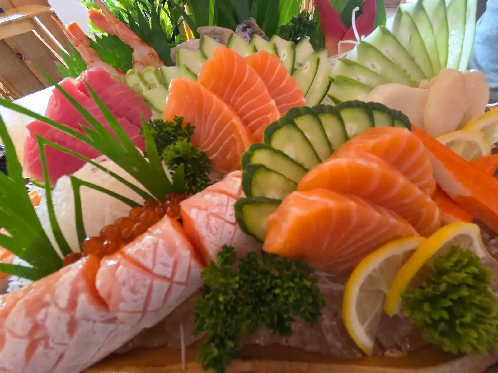 A large sashimi platter: salmon, tuna, scored salmon belly with salmon roe, prawns, cucumber and lemon