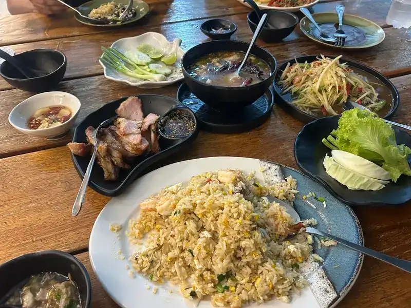 Fried rice, grilled meat, papaya salad and soup on a wooden table