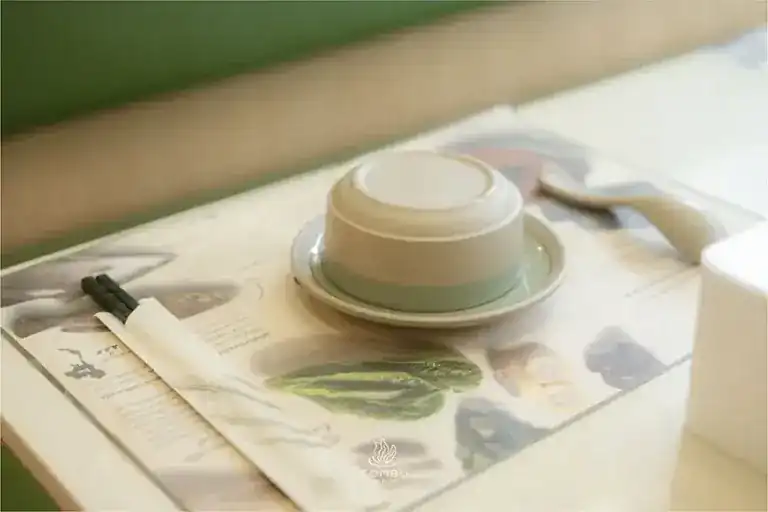 A place setting: an upturned bowl, chopsticks and a paper menu sheet