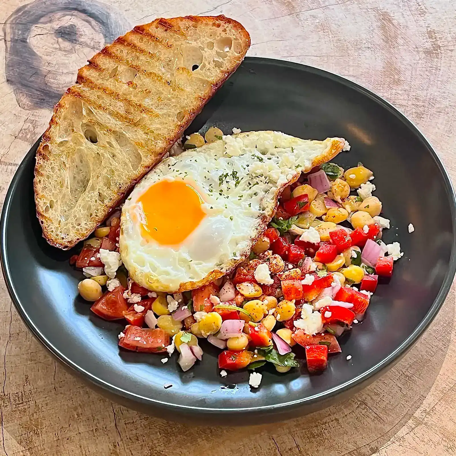 Grilled sourdough with a fried egg and a salad of chickpeas, corn, tomato and feta