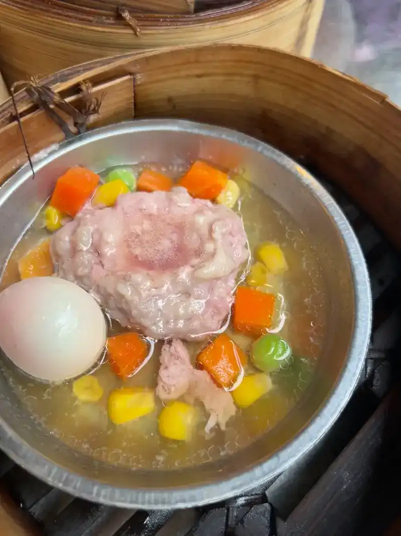 Steamed minced pork with an egg and diced vegetables, still in its steamer