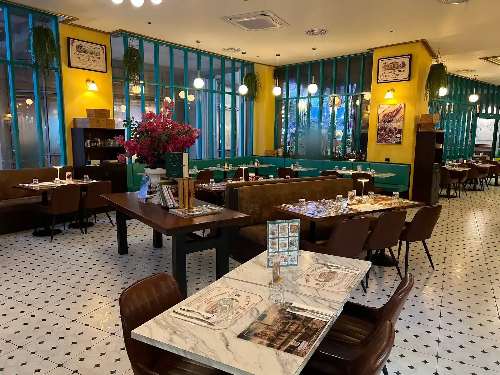 The dining room at Paname: yellow walls, teal window frames, brown banquettes and a black-and-white tiled floor