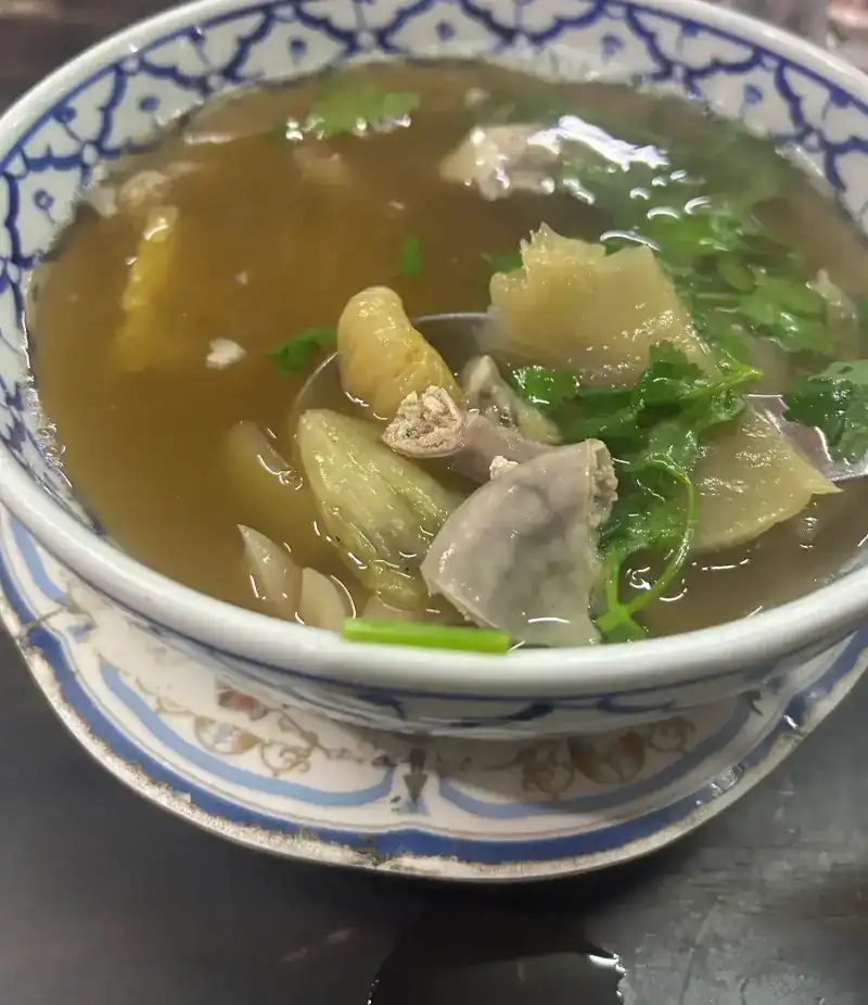 A clear soup with coriander in a blue-and-white bowl