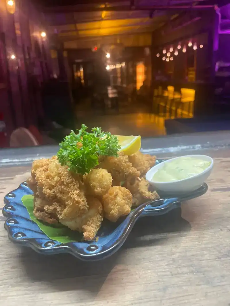 Crisp fried seafood with lemon and a pale green dip on a blue shell-shaped plate