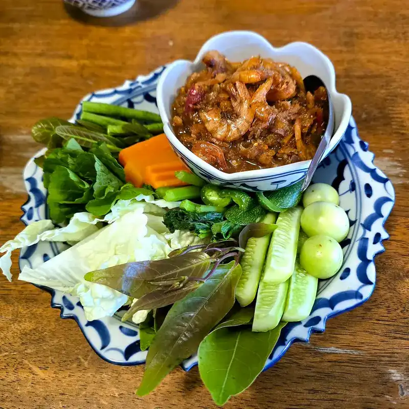 Chilli dip served with fresh vegetables on a blue and white plate