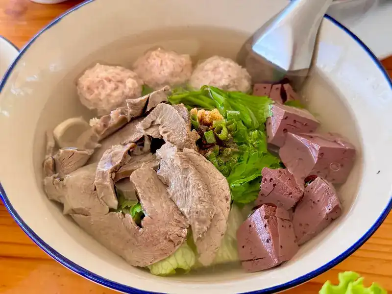 Clear noodle soup with pork balls, sliced meat and greens