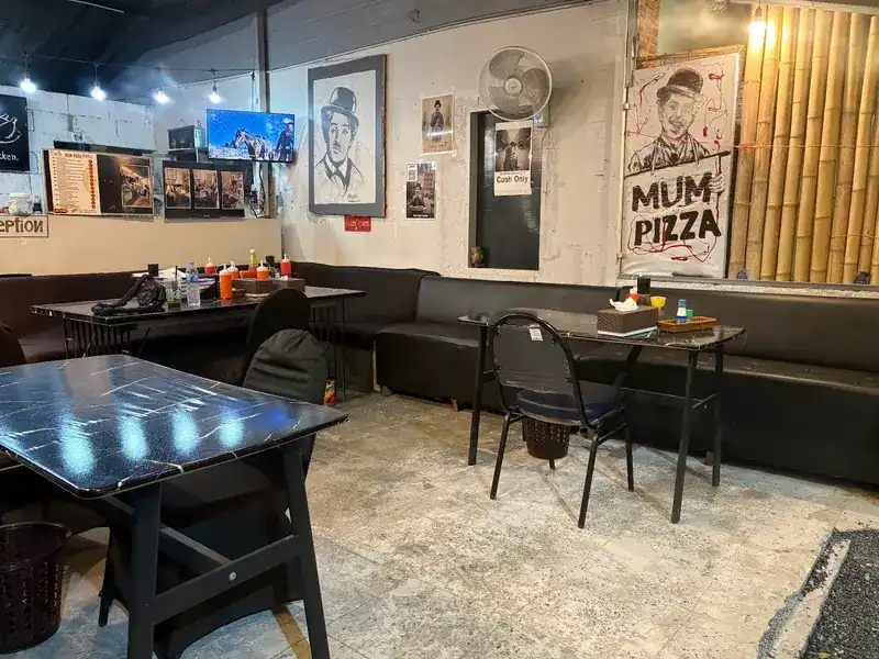 Inside the shop: black tables, a long sofa and drawings of a man in a bowler hat on the walls