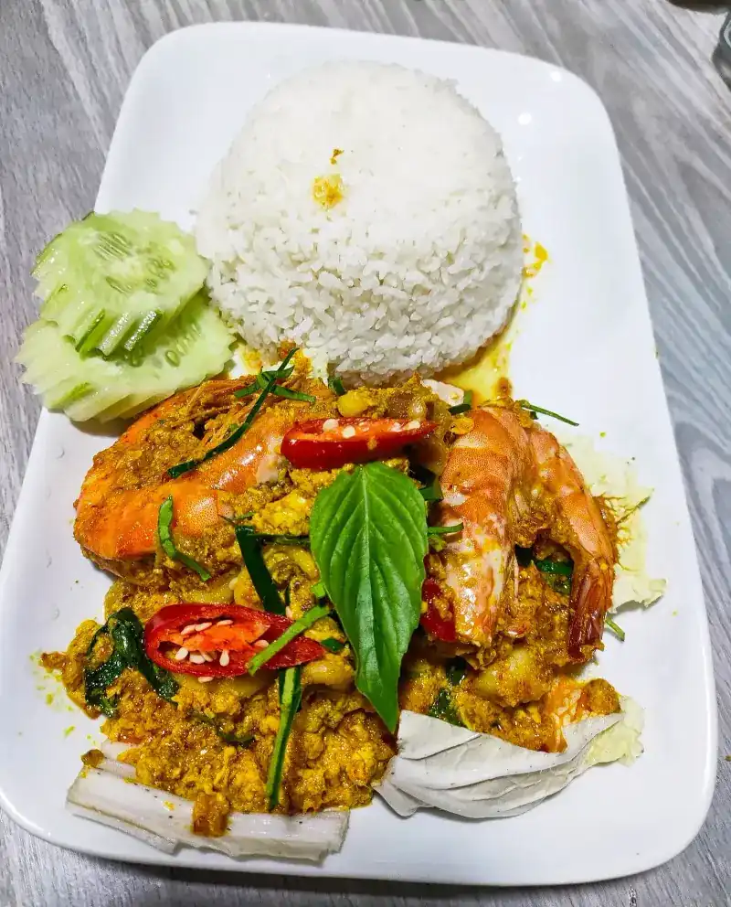 Prawns in a yellow curry sauce with rice and cucumber