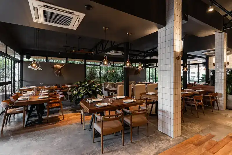 The main room with wooden tables, white tiled pillars and pendant lamps