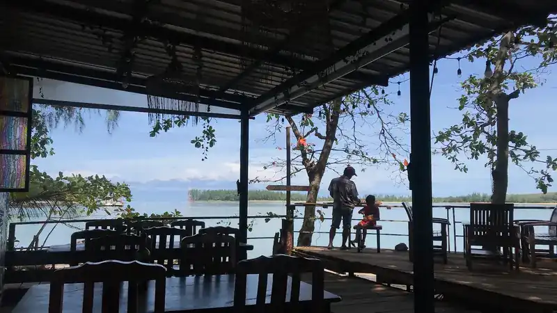 The covered deck with wooden tables, looking out over the water