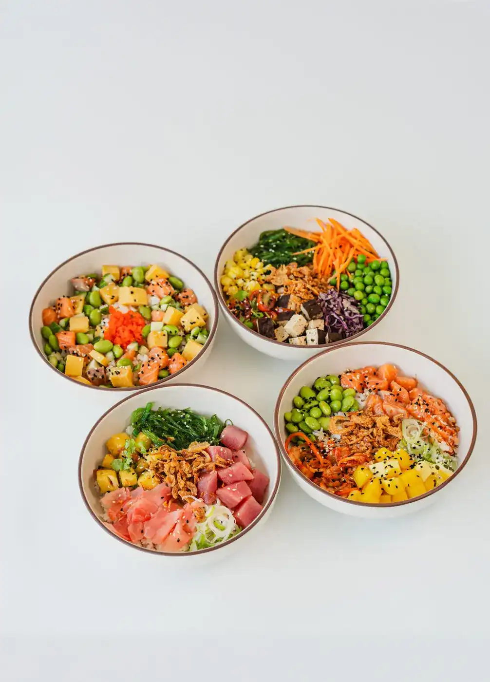 Four poke bowls with salmon, tuna, tofu, edamame, mango and seaweed