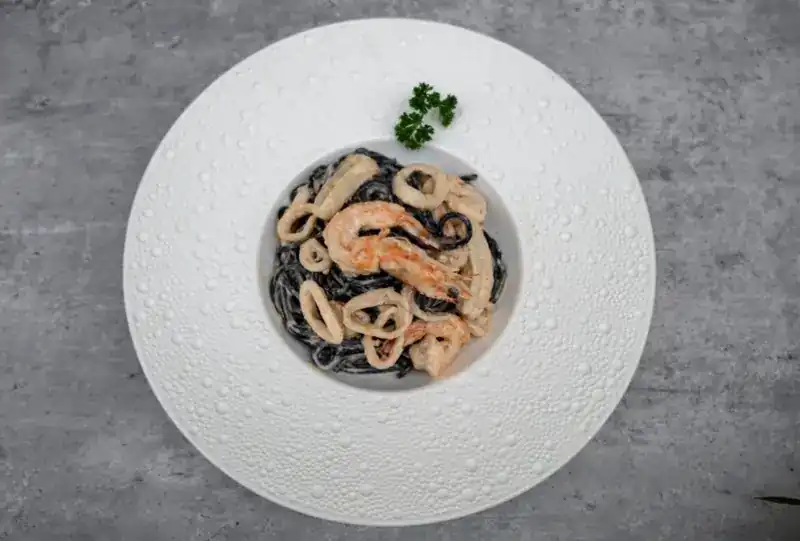 Nero pasta: black spaghetti with seafood in a white bowl