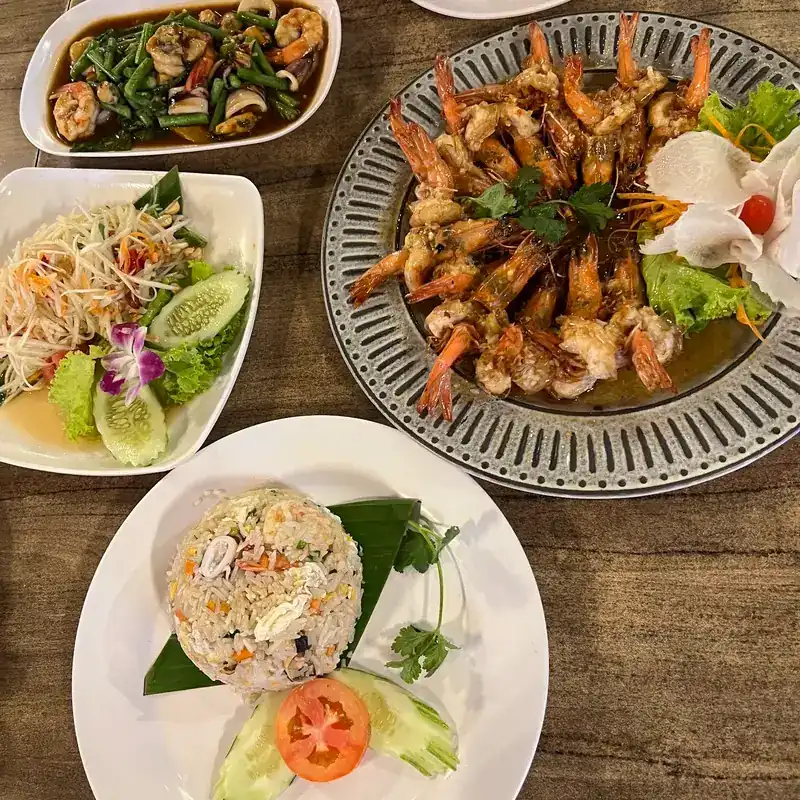 A table of dishes: prawns in sauce, papaya salad, fried rice and a prawn stir-fry with long beans