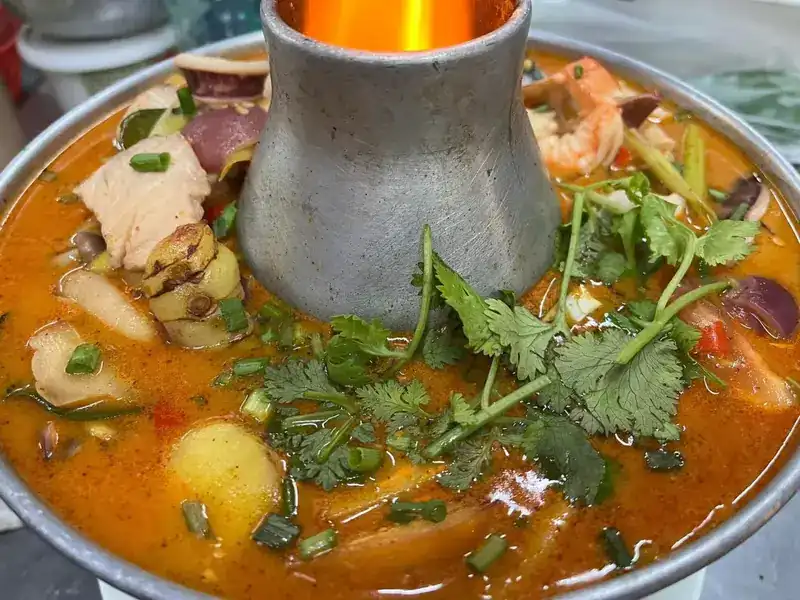 Tom yum with prawns and herbs in a hot pot with a burning chimney