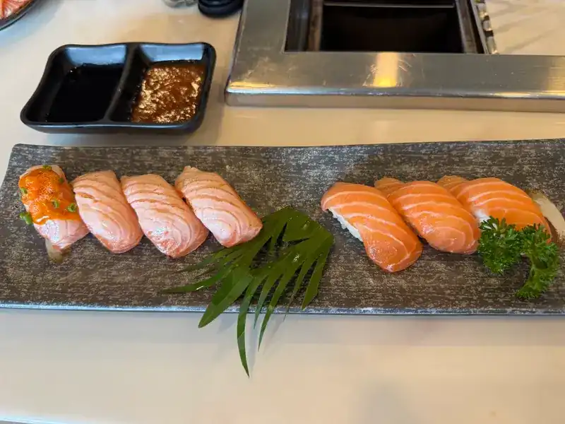 A row of salmon nigiri, torched and plain