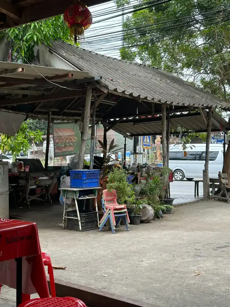 The open sala beside the road, with a tin roof, potted plants and a parked van