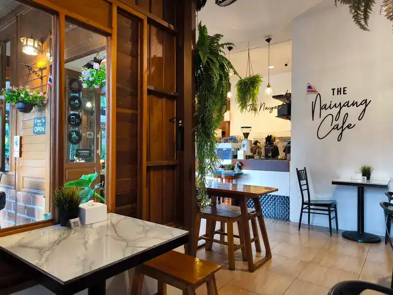 Inside the cafe: marble-top tables, hanging ferns and the cafe's name on the white wall