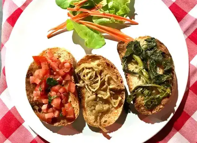 Three bruschette: chopped tomato, marinated eggplant and broccoli rabe