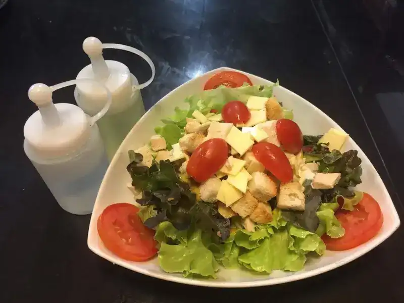 Green salad with tomato, cheese and croutons, with dressing on the side