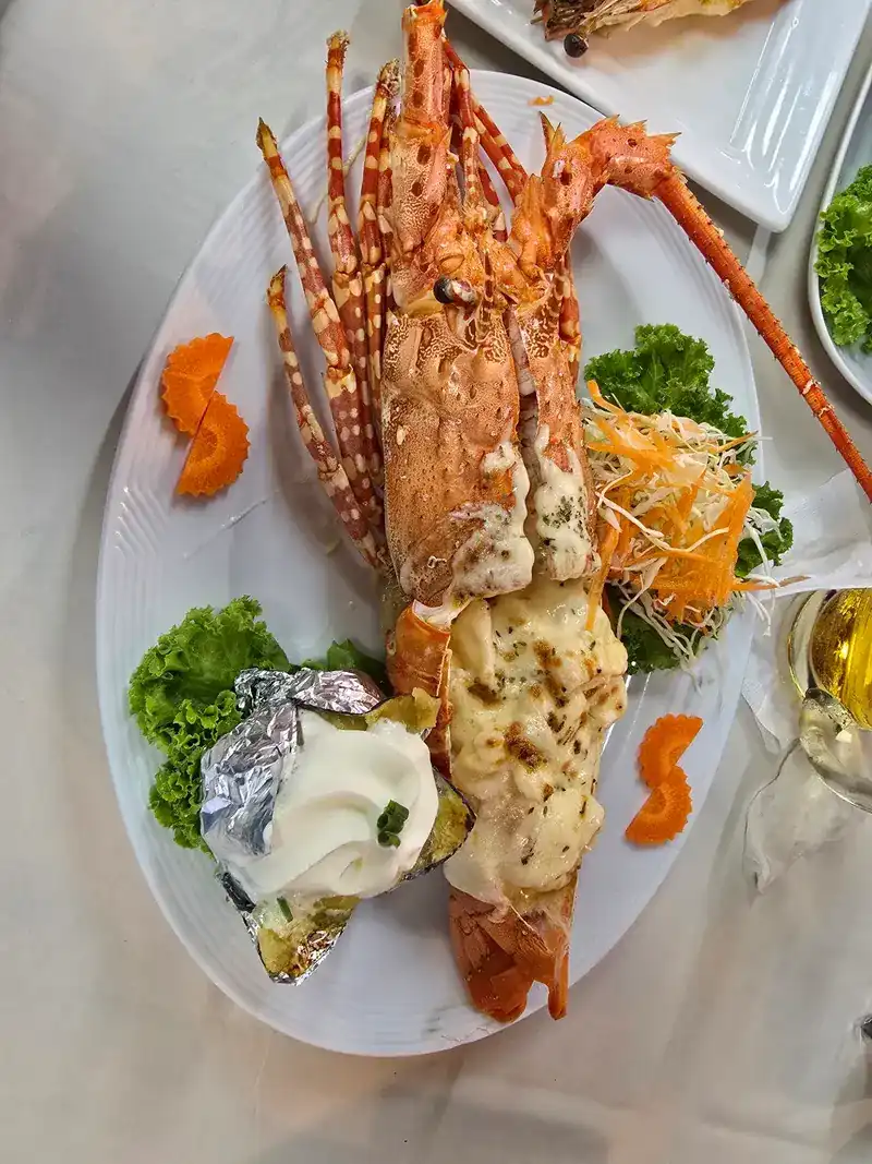 Lobster halves baked with a golden topping, with salad and a potato in foil