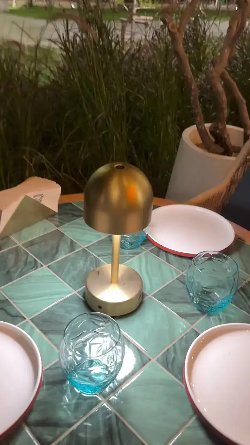 A brass table lamp and blue glasses on a green tiled table at night