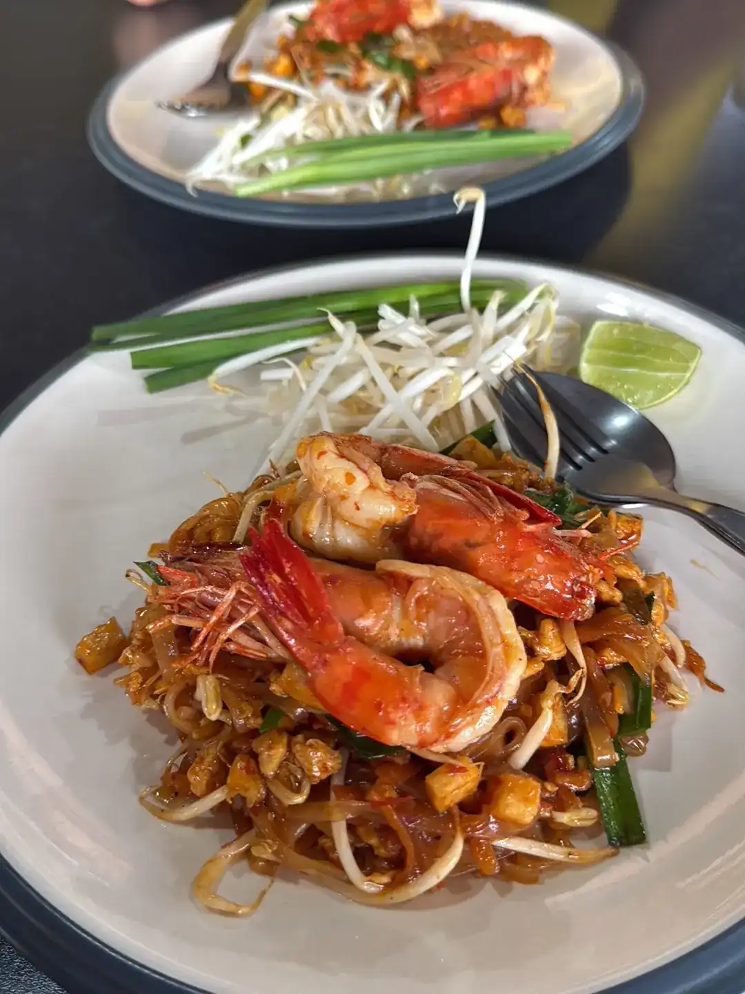 Pad thai with two large prawns, bean sprouts, spring onion and a wedge of lime