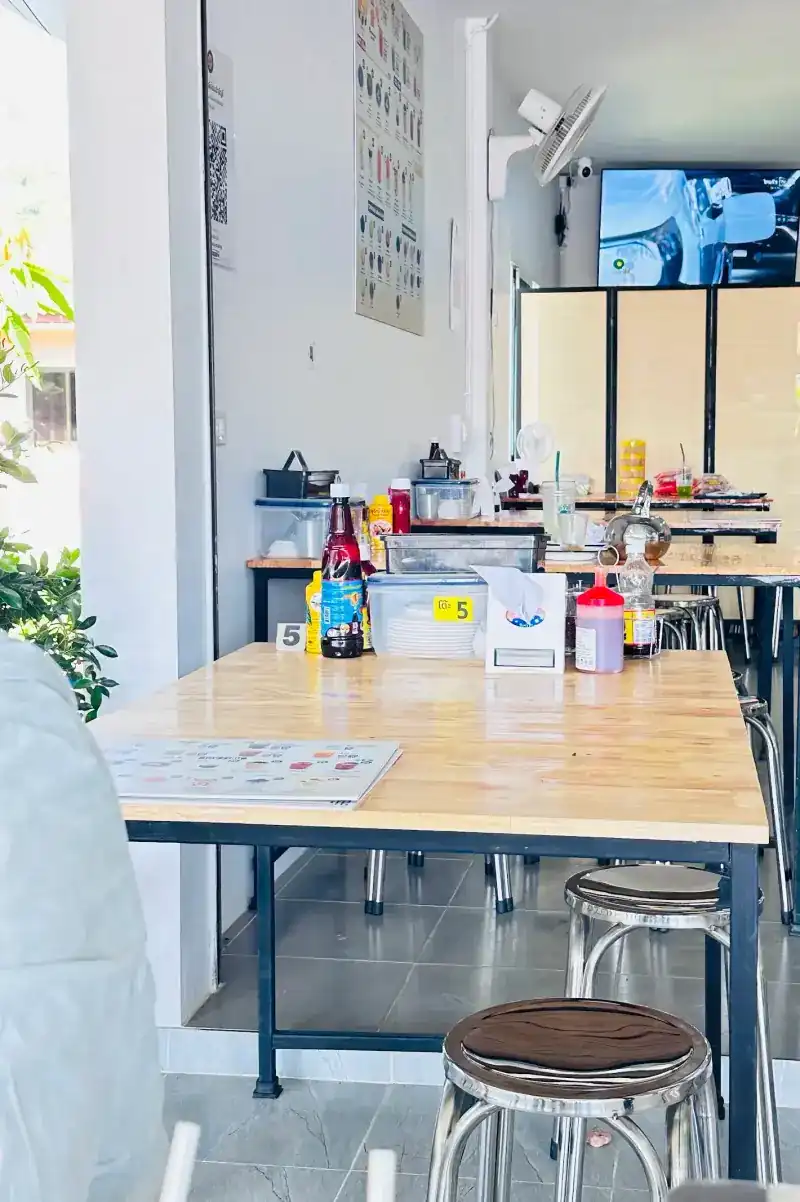 Inside the shop: wooden tables with steel stools, table number 5 and the soy milk menu on the wall