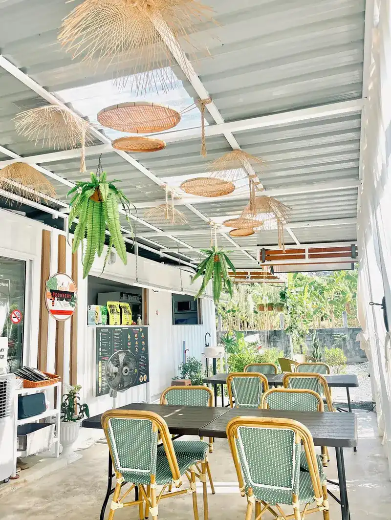 The terrace with green rattan chairs, ferns and wicker lamps