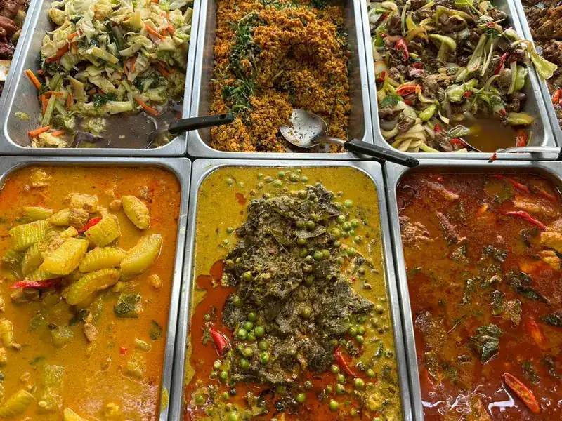 Trays of yellow curry, green curry with peas, stir-fried vegetables and a fried dish