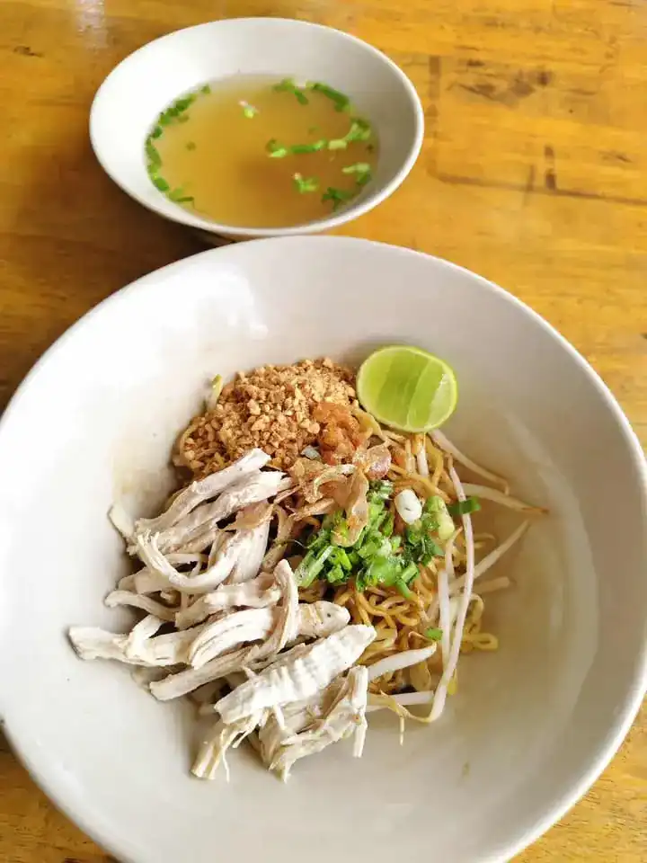 Dry noodles with shredded chicken, peanuts and lime, a cup of clear soup behind