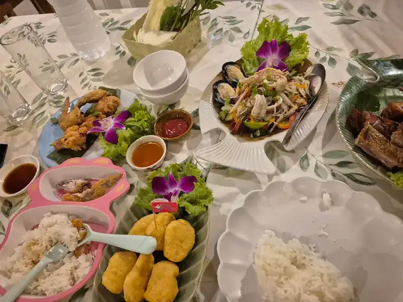 A shared table: papaya salad with mussels, fried chicken, dipping sauces and rice