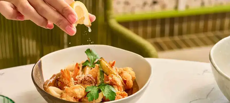 Lemon squeezed over a bowl of frittura mista