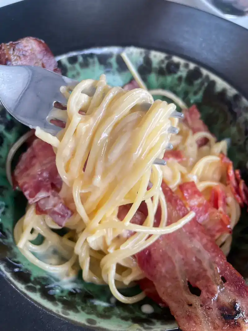 Spaghetti twirled on a fork with crisp bacon