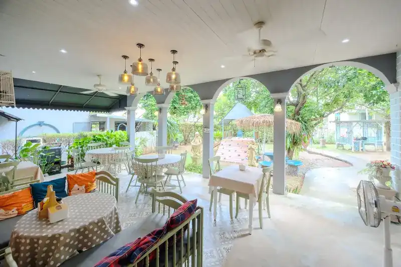 The covered veranda, with tables and cushioned benches looking out through white arches to the garden