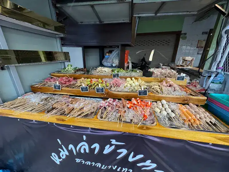 Long counter of skewer trays on ice under the stall's black banner with the shop's name