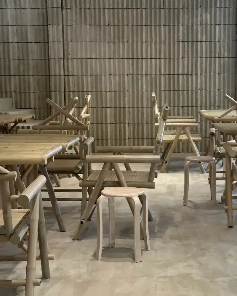 The dining room: bamboo tables and chairs in front of a ribbed concrete wall