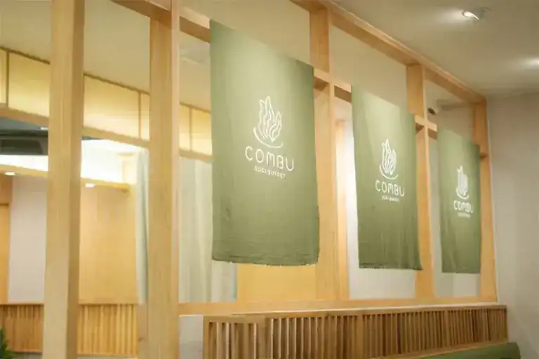 Sage-green cloth banners hanging in a pale timber frame inside the restaurant