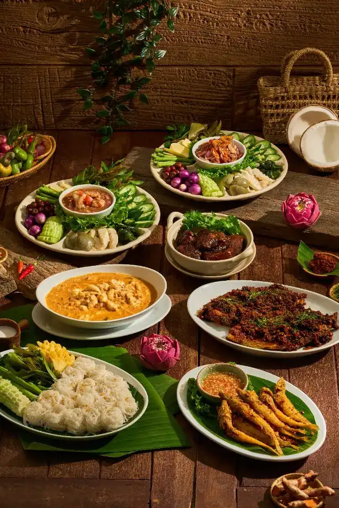 A table of southern Thai dishes: curry, chilli dips with vegetables, rice noodles and fried fish
