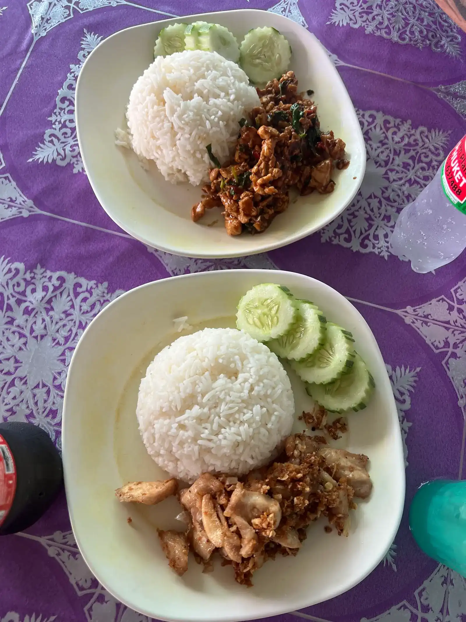 Basil chicken and garlic chicken, each with rice and cucumber, on a purple tablecloth / ข้าวกะเพราไก่และไก่ทอดกระเทียม พร้อมข้าวสวยและแตงกวา บนโต๊ะผ้าปูสีม่วง